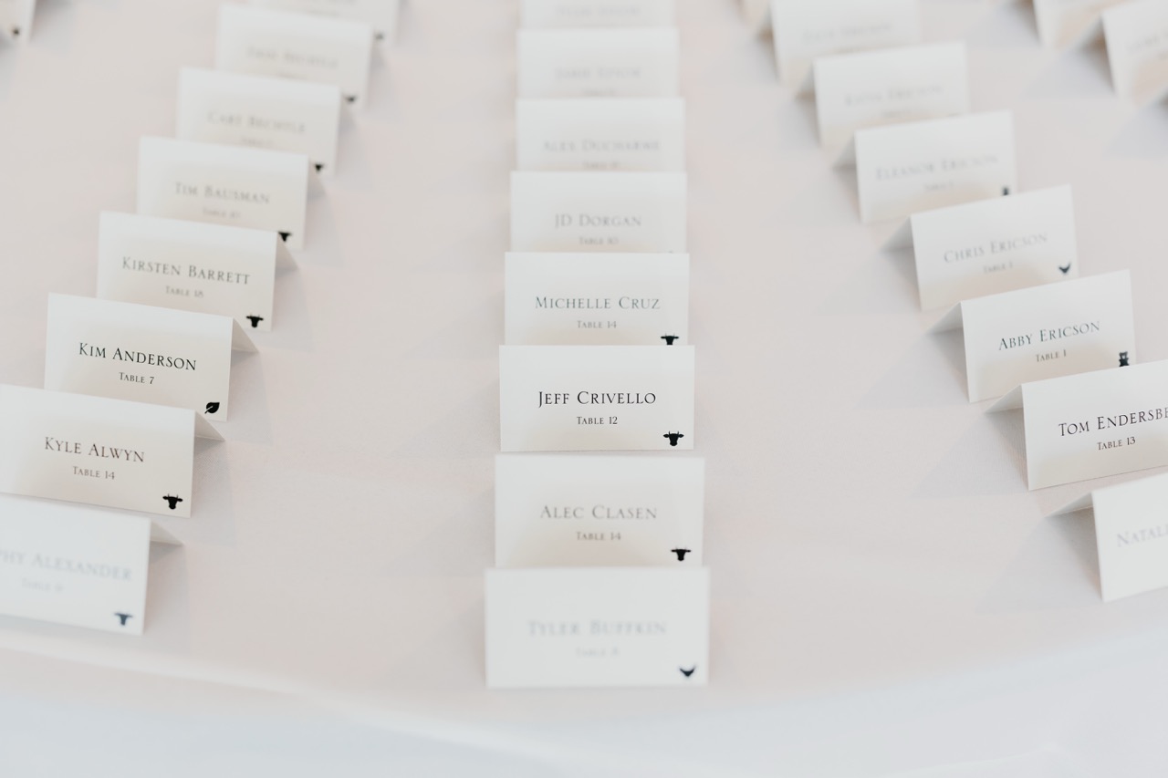 Close up of white wedding escort cards with black meal choice icon stickers showing cow and leaf options for catering at the Whim in Minnesota.